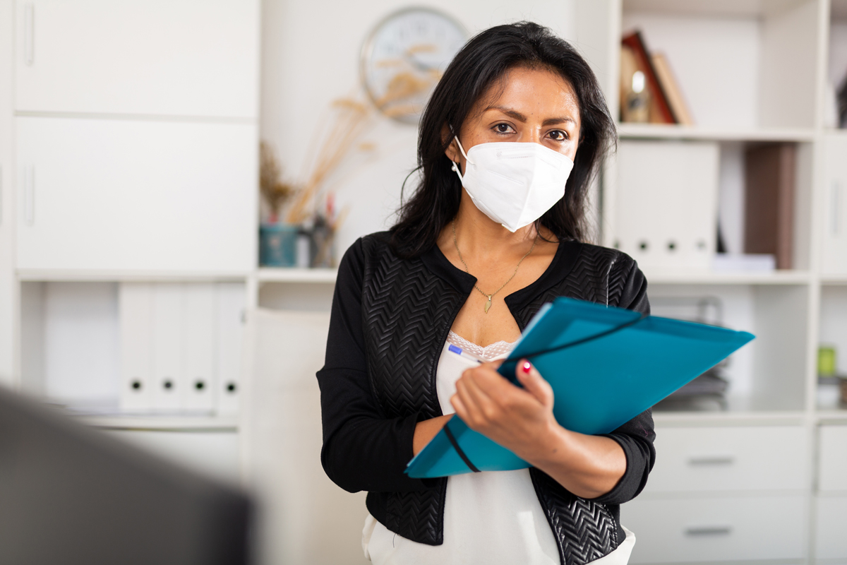 female healthcare professional wearing mask and holding clipboard of paper